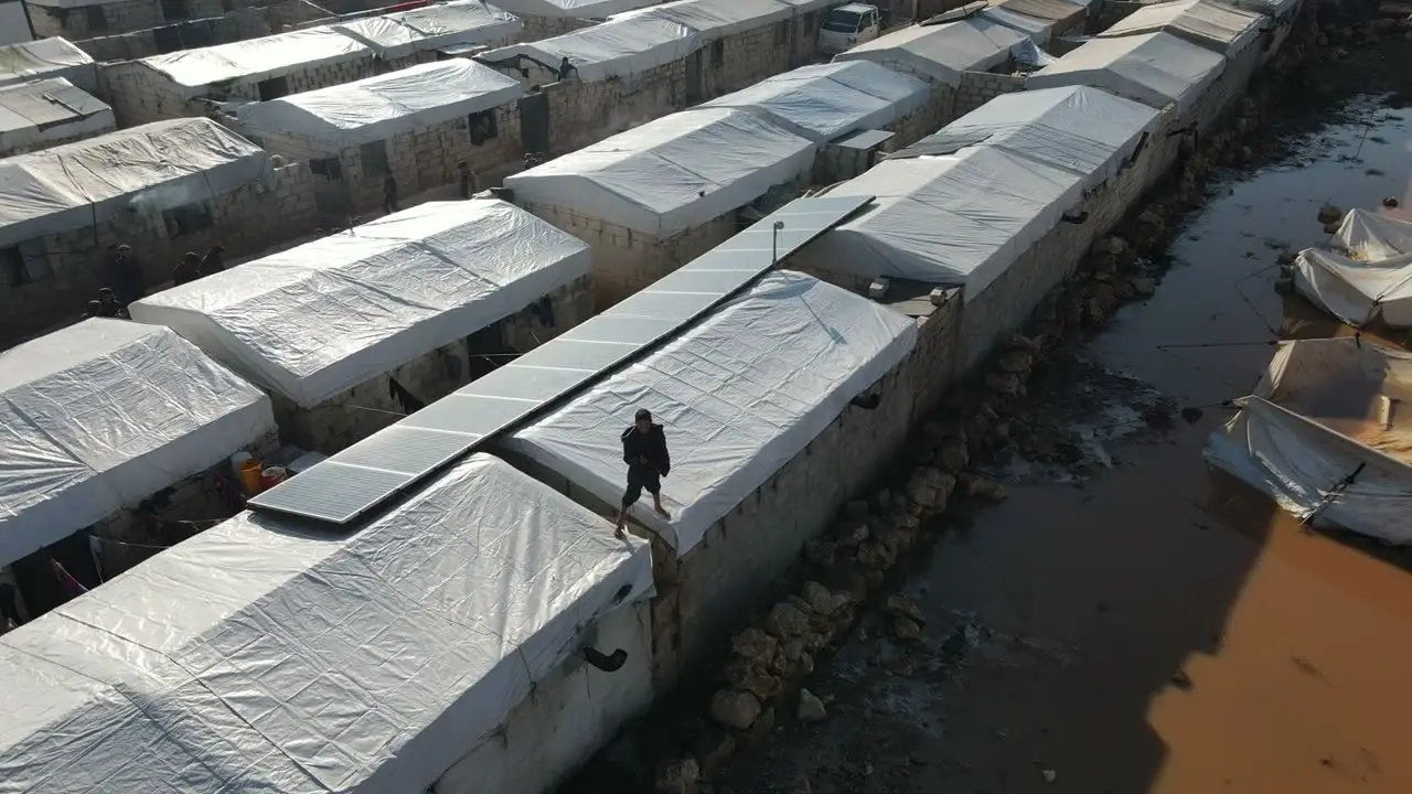 Aerial view of a flooded settlement, rooftops beside brown water